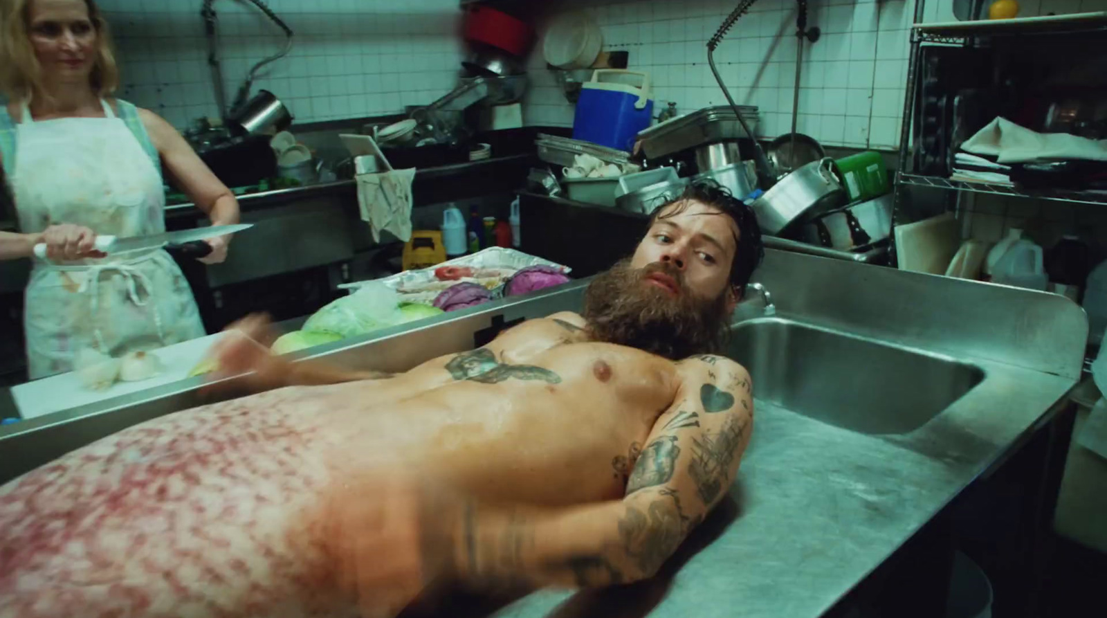 a man laying on a sink in a kitchen