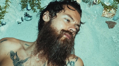 a man with a long beard laying on the beach