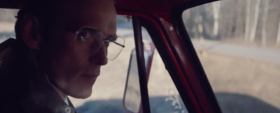 a man wearing glasses sitting in a car