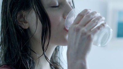 a woman drinking a glass of water from a bottle