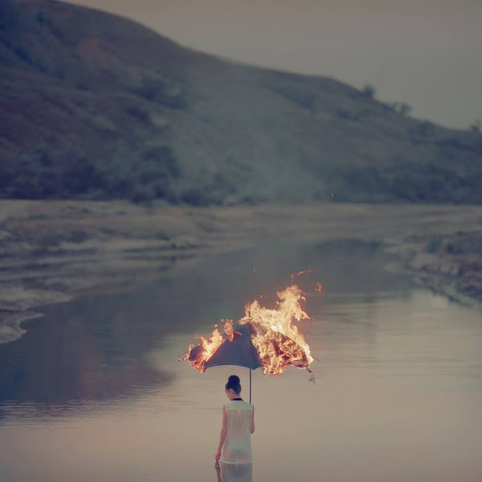 a woman standing in the water holding a fire umbrella