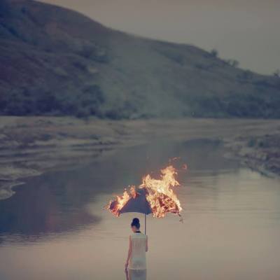 a woman standing in the water holding a fire umbrella