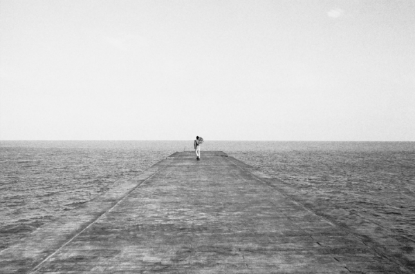 a person standing on a pier in the middle of the ocean