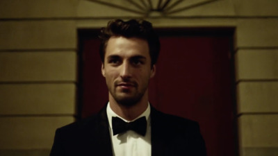 a man in a tuxedo standing in front of a door