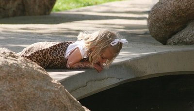 a little girl laying on the ground next to a rock