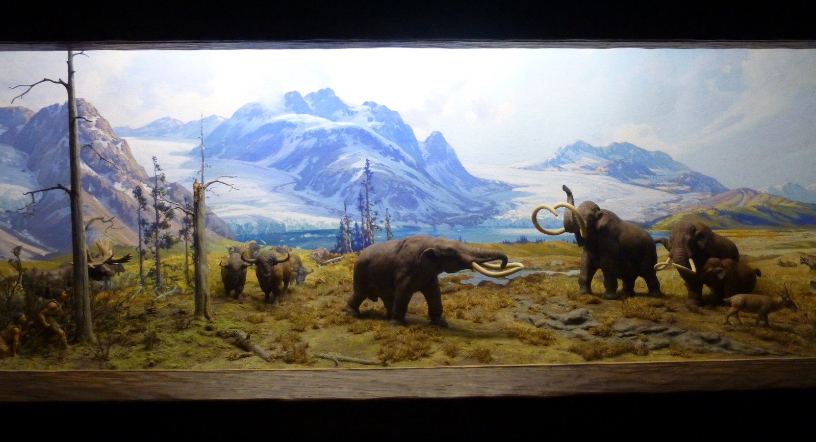 a painting of elephants in a field with mountains in the background