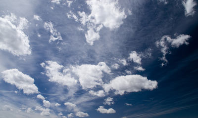 a blue sky filled with white clouds and a plane flying in the sky