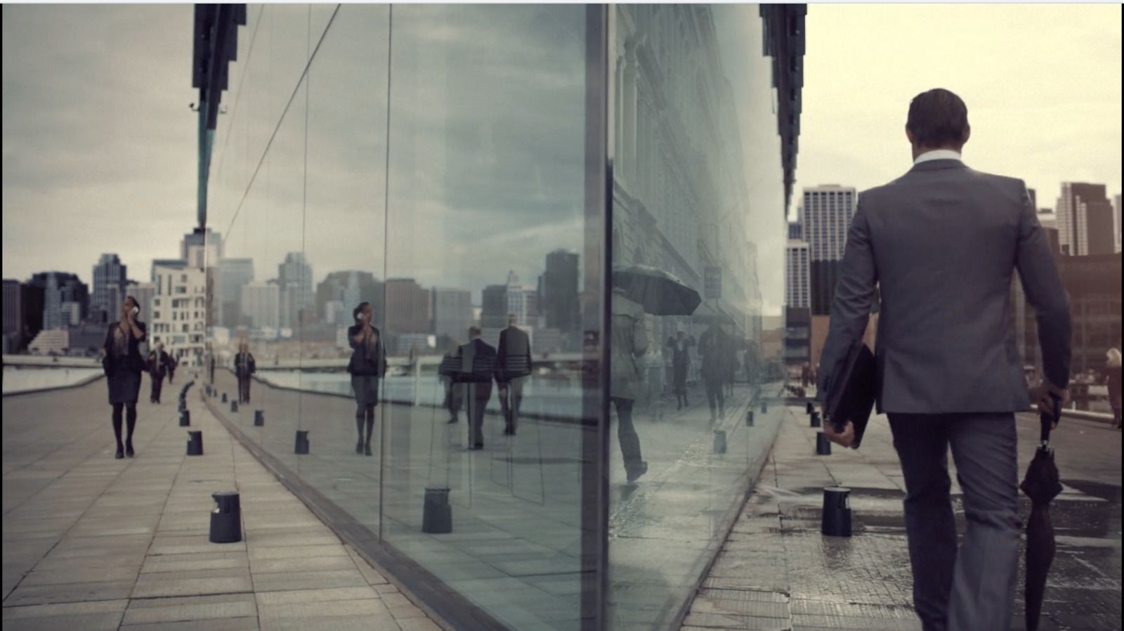 a group of people walking down a sidewalk next to a tall building