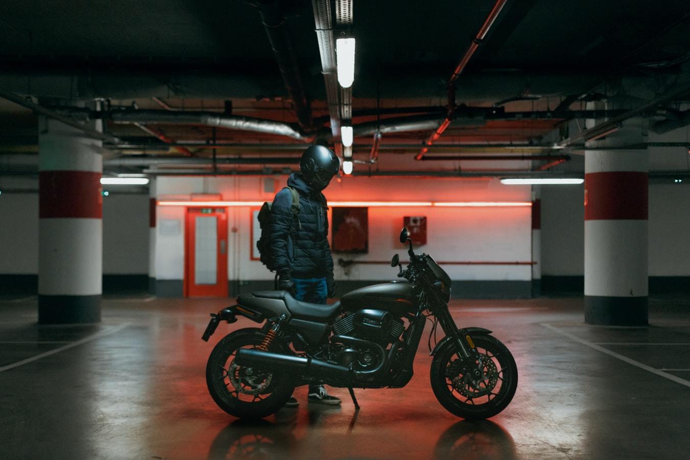 a man standing next to a motorcycle in a parking garage