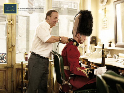 a man in a red uniform cutting another man's hair