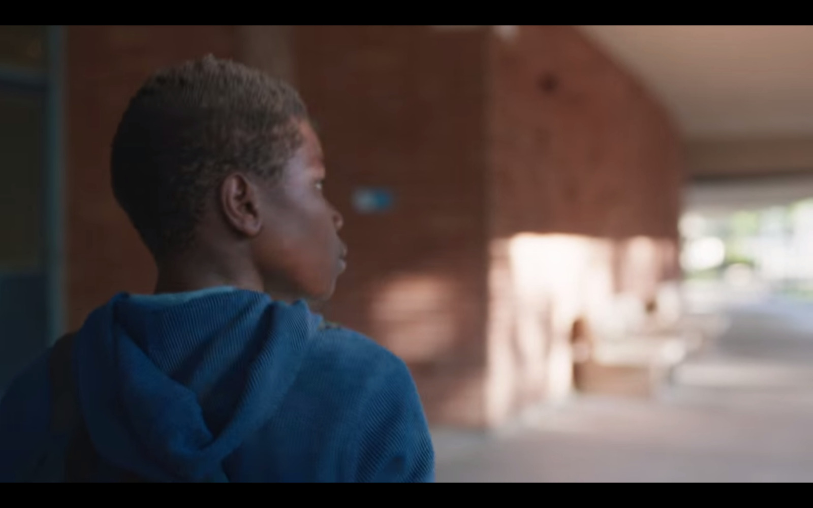 a boy in a blue hoodie looking off into the distance