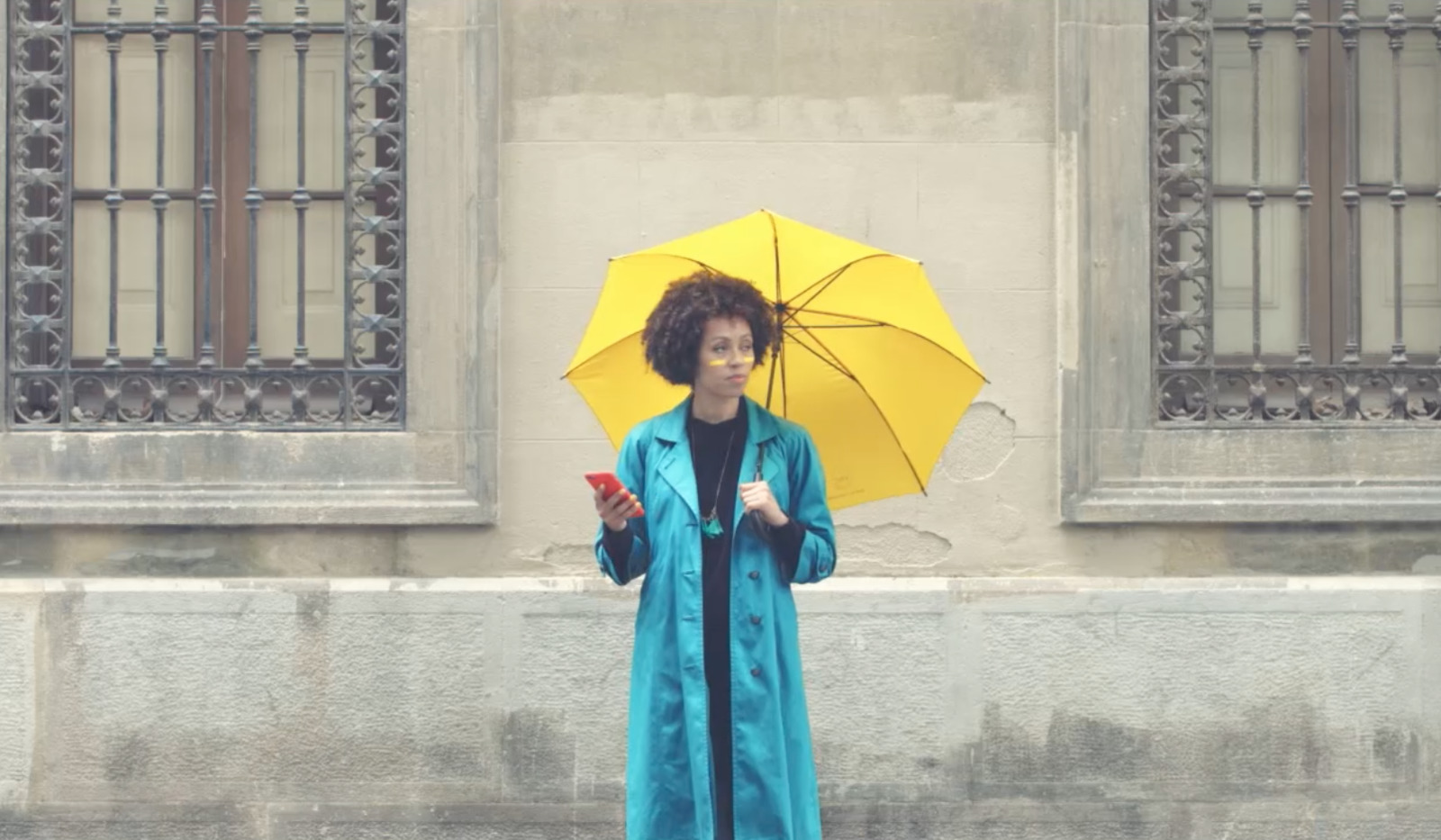 a woman in a blue coat holding a yellow umbrella