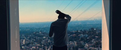 a man standing in front of a window looking out at a city