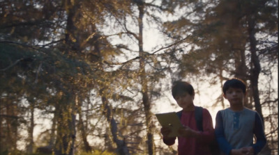 a couple of kids standing next to each other in a forest