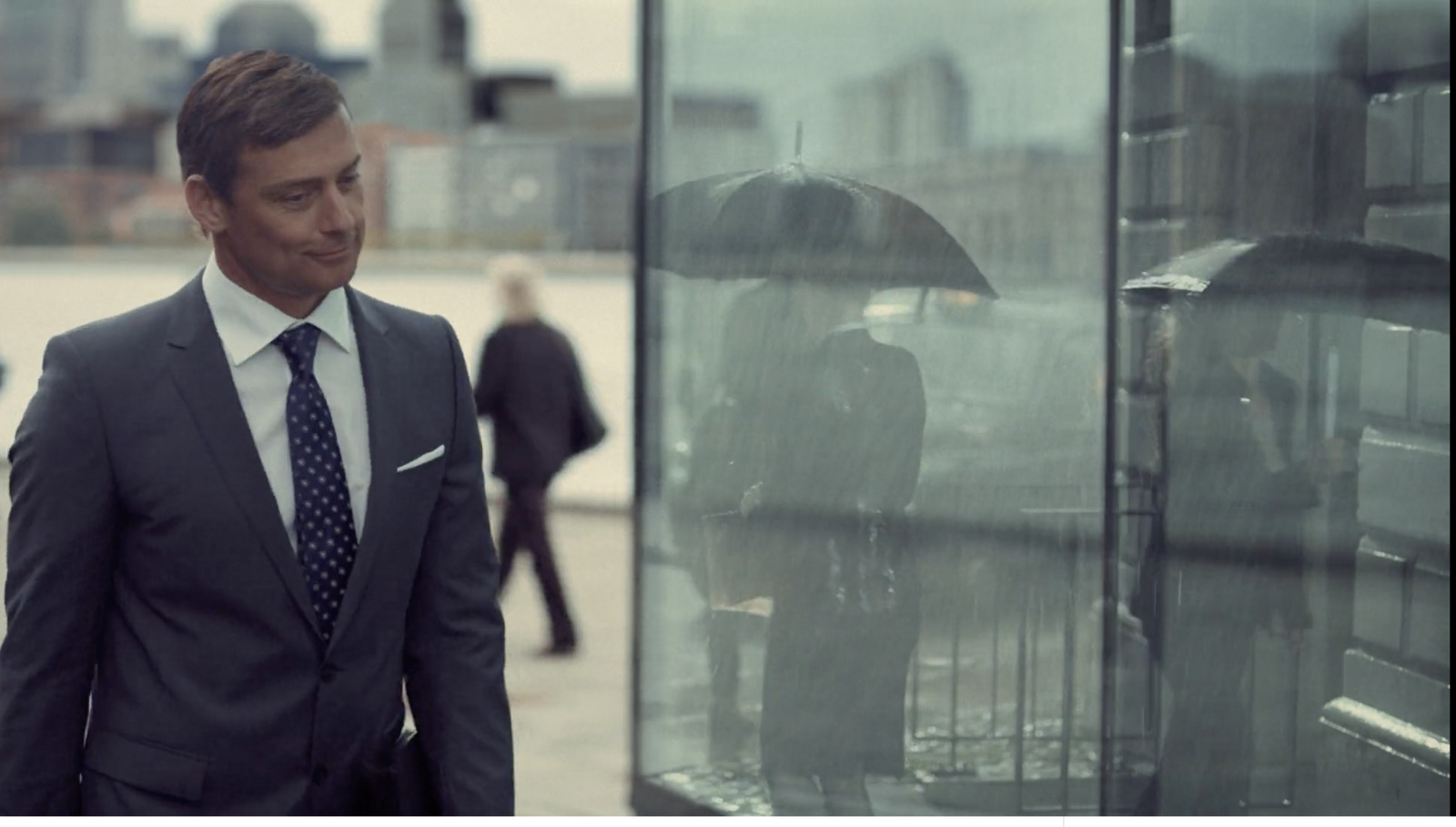 a man in a suit and tie standing in front of a glass case