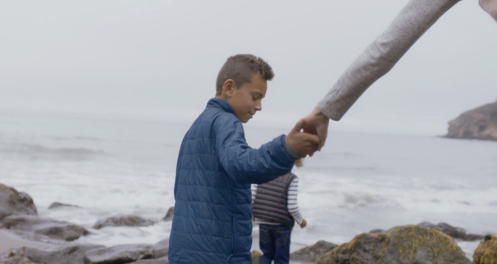 a young boy holding a baseball bat on a beach