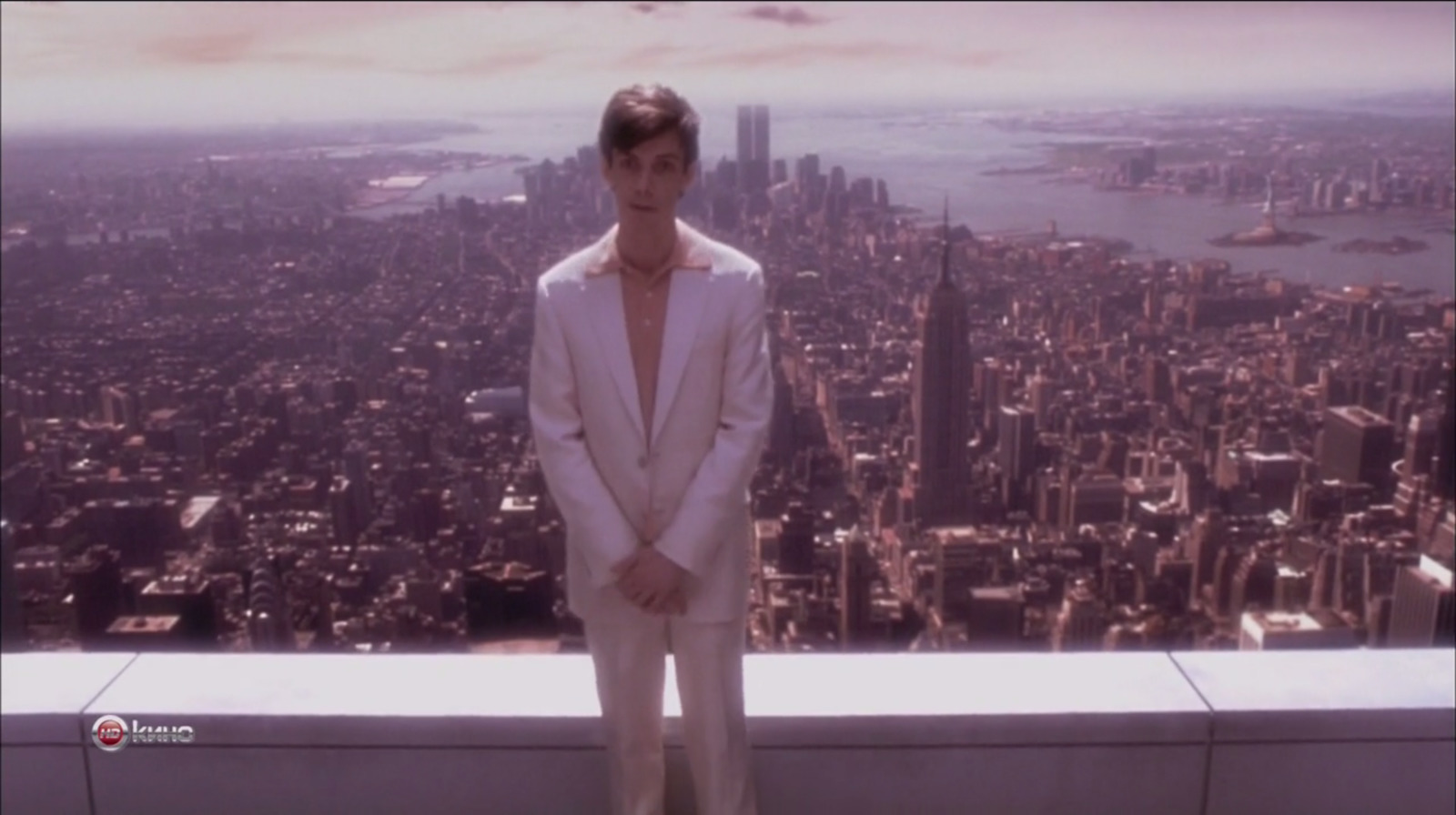 a man in a white suit standing on top of a building