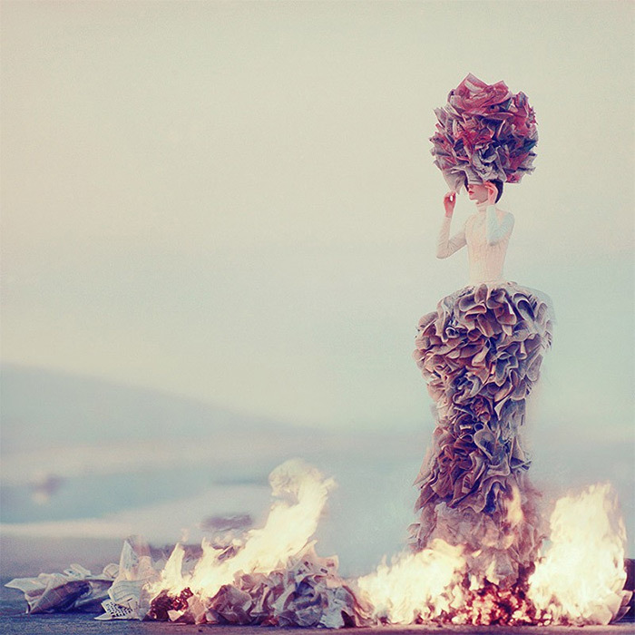 a woman standing on top of a pile of paper next to a fire