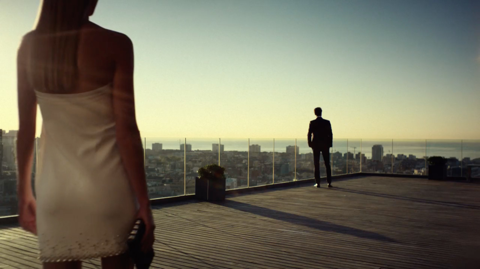 a man and a woman standing on a balcony overlooking a city