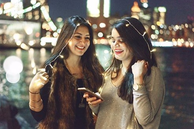 two women standing next to each other looking at a cell phone