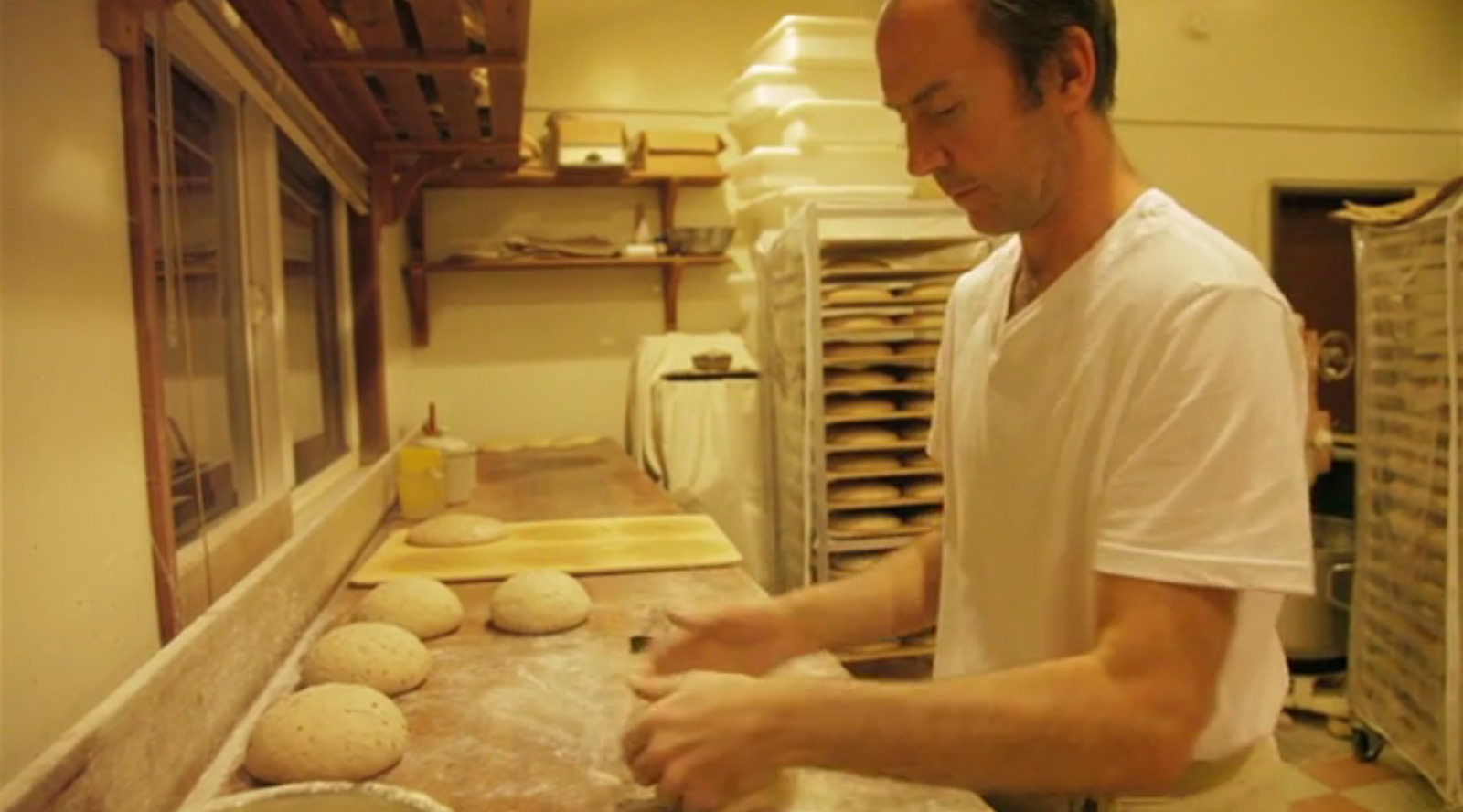 a man in a kitchen making bread on a counter