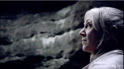 a woman standing in front of a stone wall