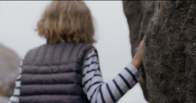 a woman standing next to a large rock