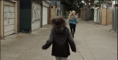 two women walking down a sidewalk next to a building