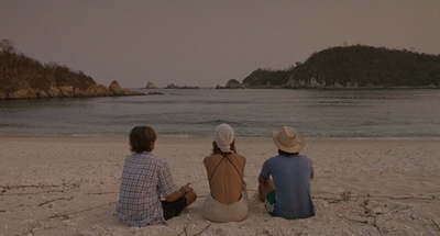 a couple of people sitting on top of a sandy beach