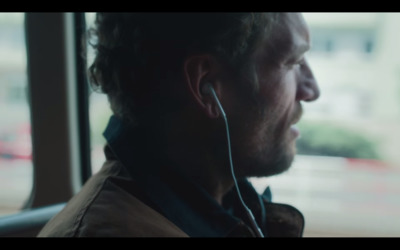 a man with ear buds in his ears looking out a window