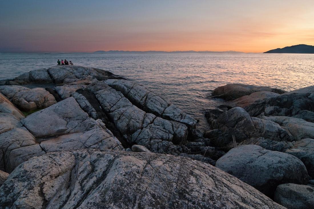 a group of people standing on top of a rocky beach