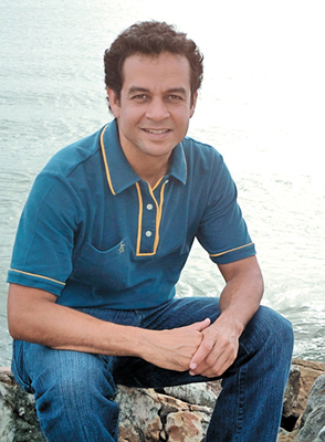 a man sitting on a rock next to the ocean