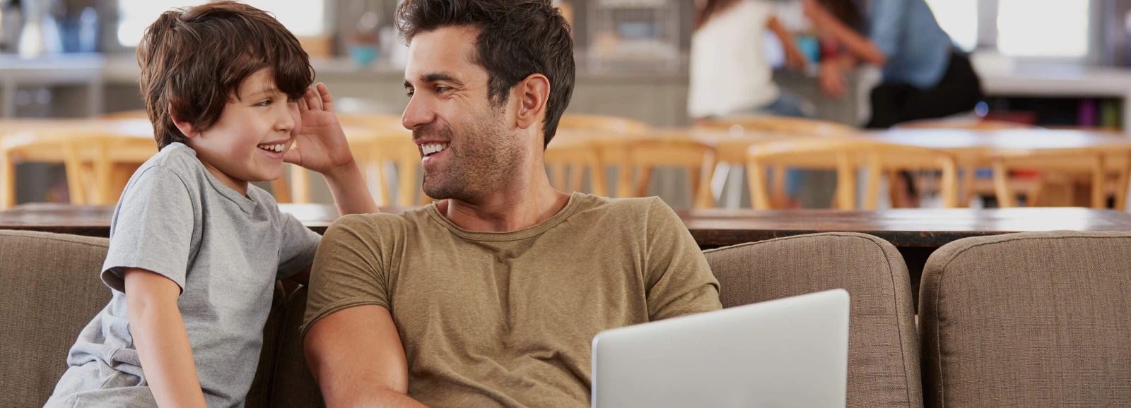 a man and a boy sitting on a couch with a laptop