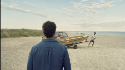 a man standing on a beach next to a boat