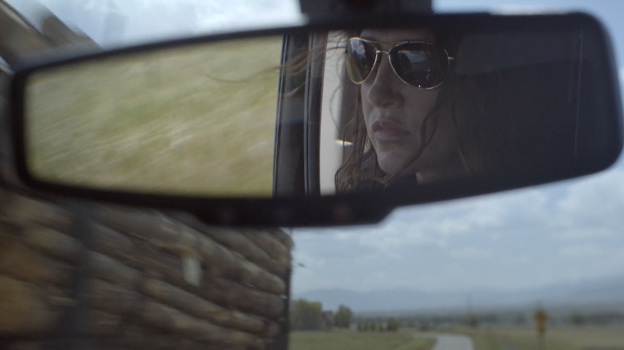 a rear view mirror of a woman in sunglasses