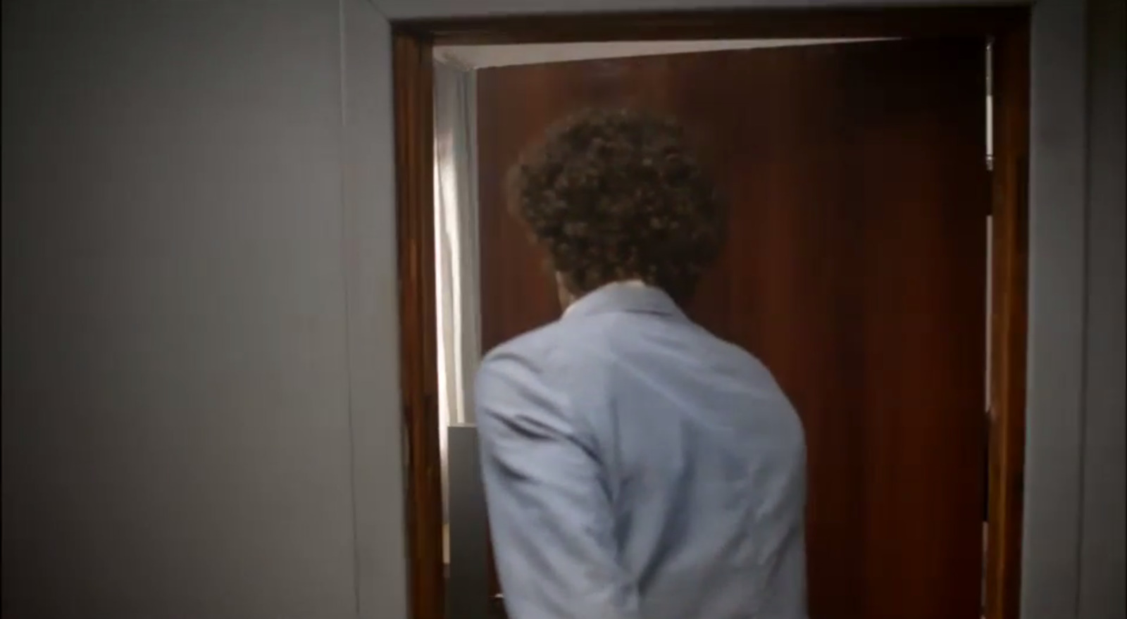 a man in a white suit standing in front of a door