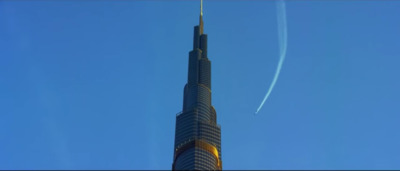 a tall building with a plane flying in the sky