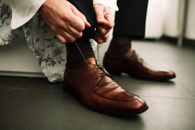 a man tying his shoes with a pair of scissors