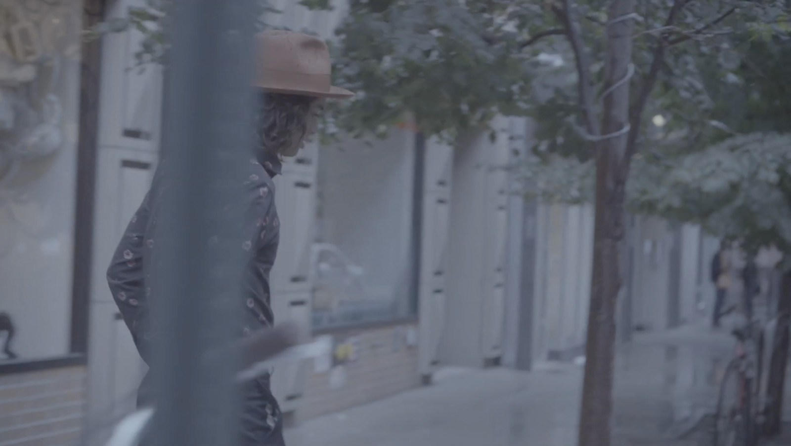 a man walking down a street next to a tree