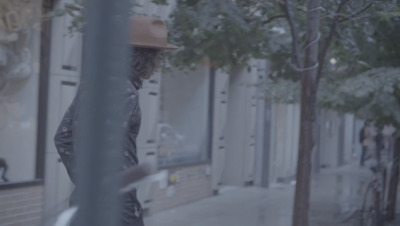 a man walking down a street next to a tree