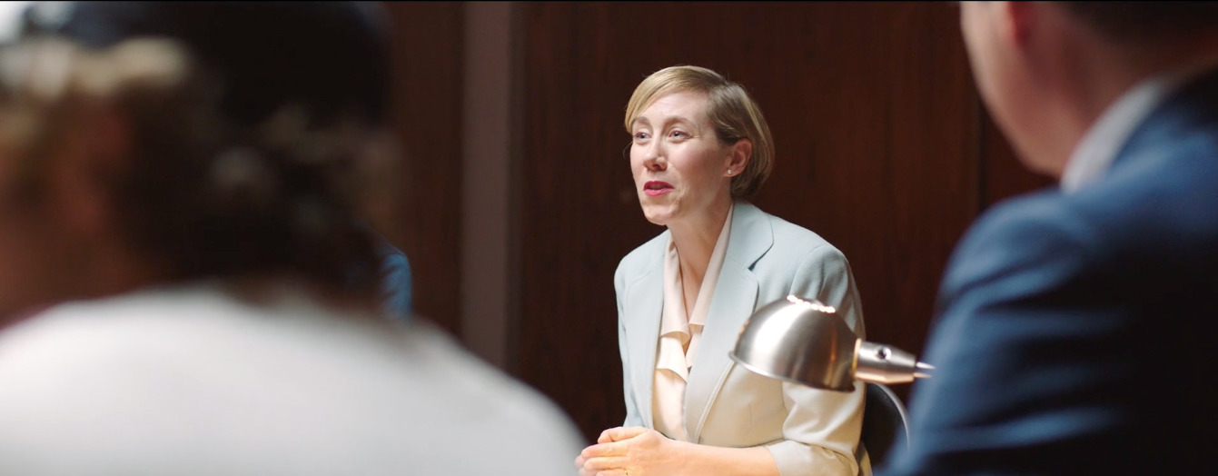 a woman in a suit speaking to a group of people