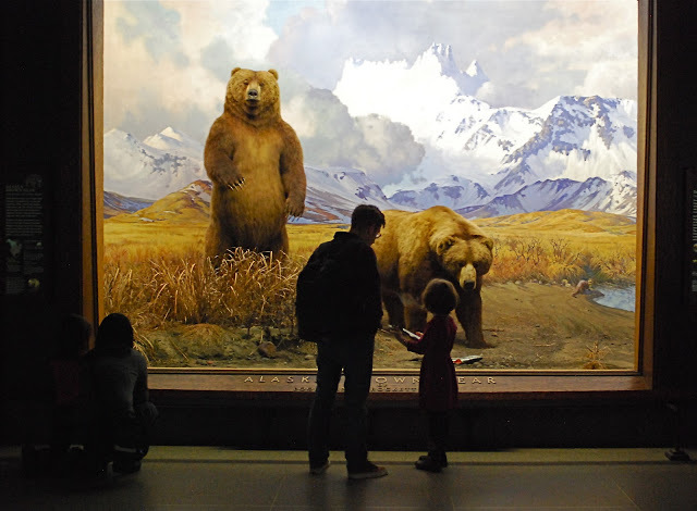 a group of people standing in front of a painting of bears