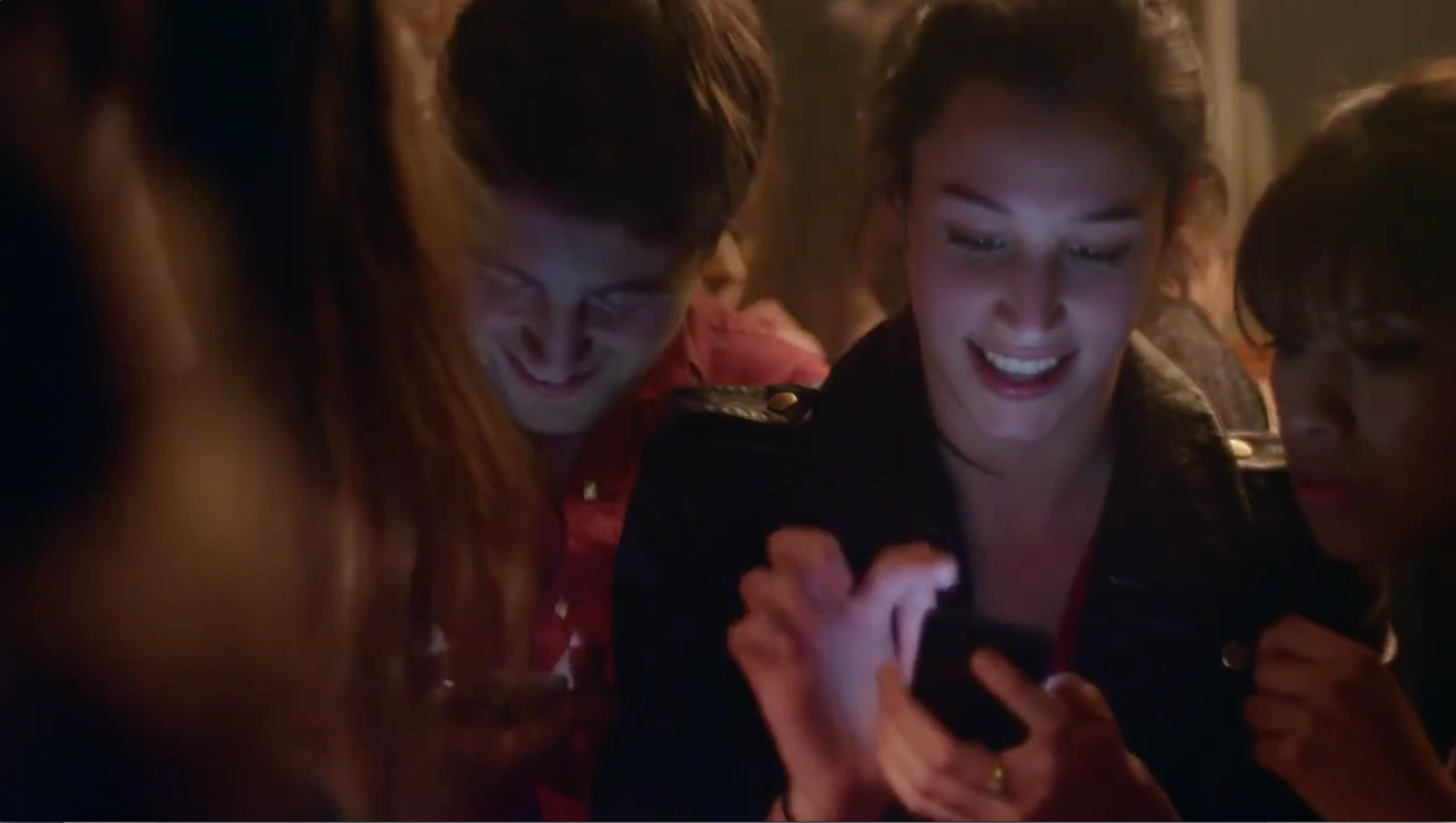 a group of young women looking at a cell phone