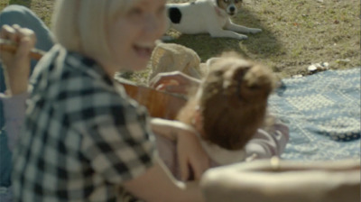 a woman sitting on a blanket with a dog in the background