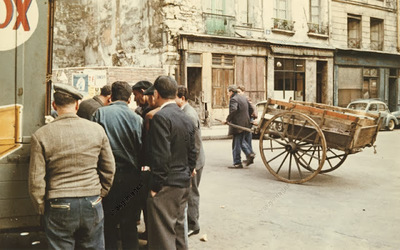 a group of men standing next to a wooden cart