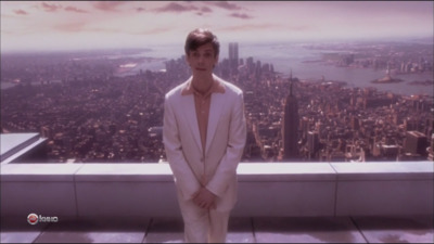 a man in a white suit standing on top of a building