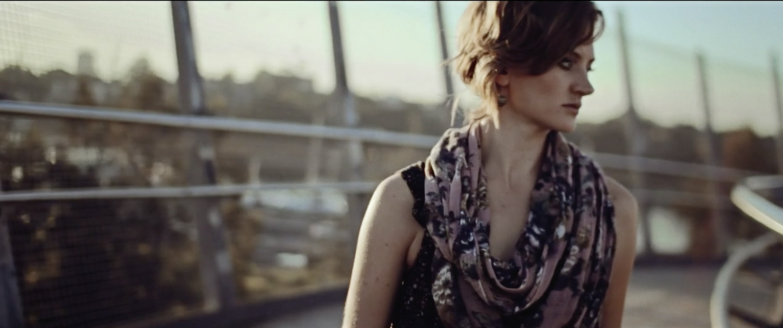 a woman standing on a bridge with a scarf around her neck