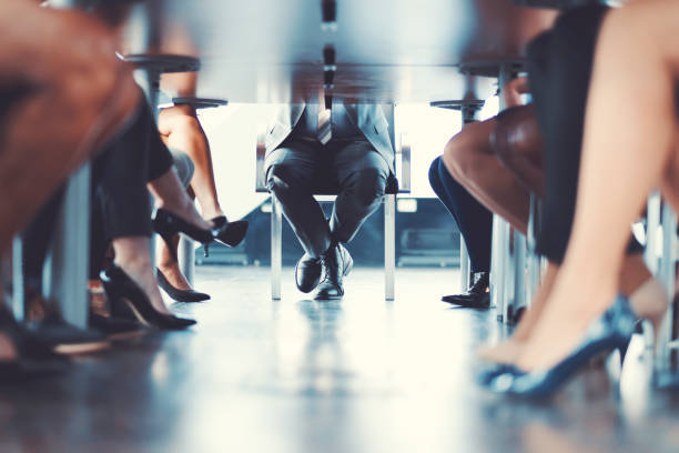 a group of people sitting at a table with their legs crossed