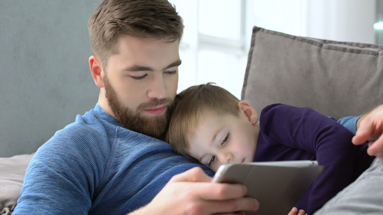 a man holding a child while looking at a tablet