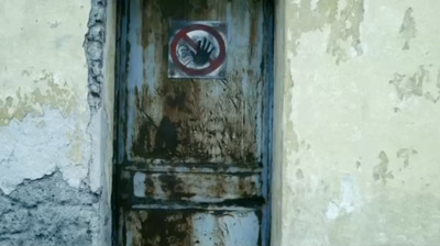 a rusted door with a no hand sign on it